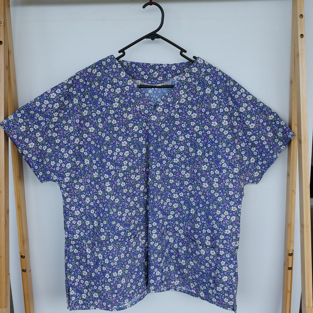 Blue floral scrub top in a wooden frame on a white background