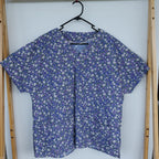 Blue floral scrub top in a wooden frame on a white background