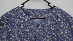 Blue and purple floral scrub top in a wooden frame on a white background
