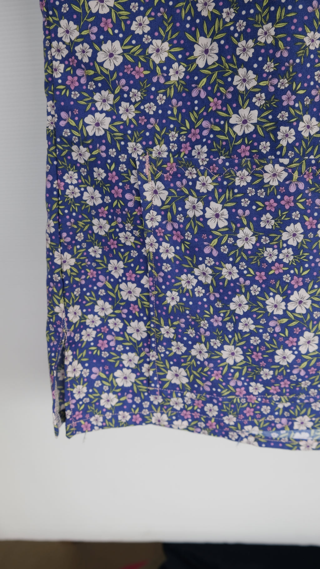 Blue and purple floral scrub top in a wooden frame on a white background