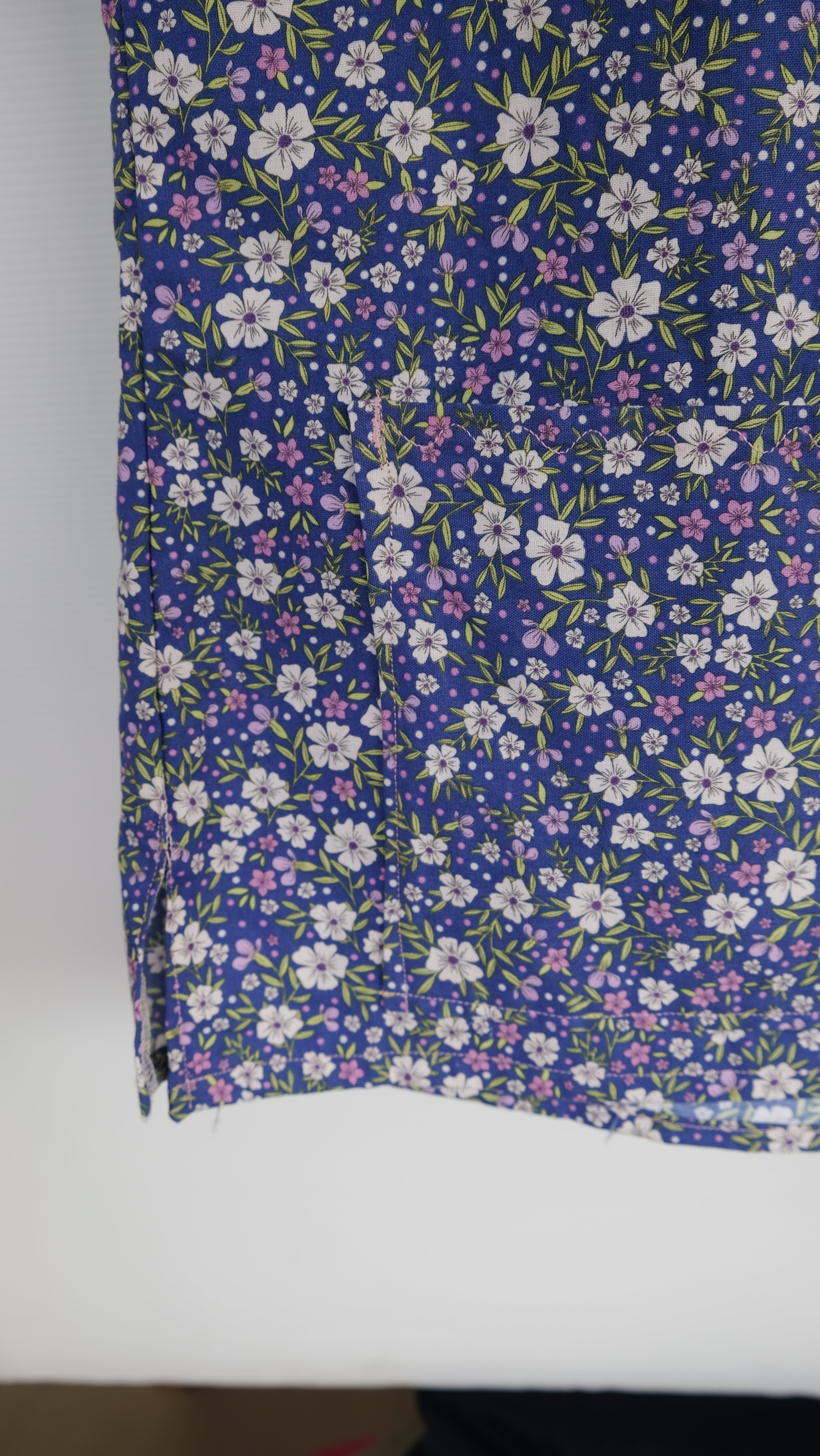 Blue and purple floral scrub top in a wooden frame on a white background