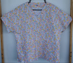 Floral-patterned scrub top on a hanger 