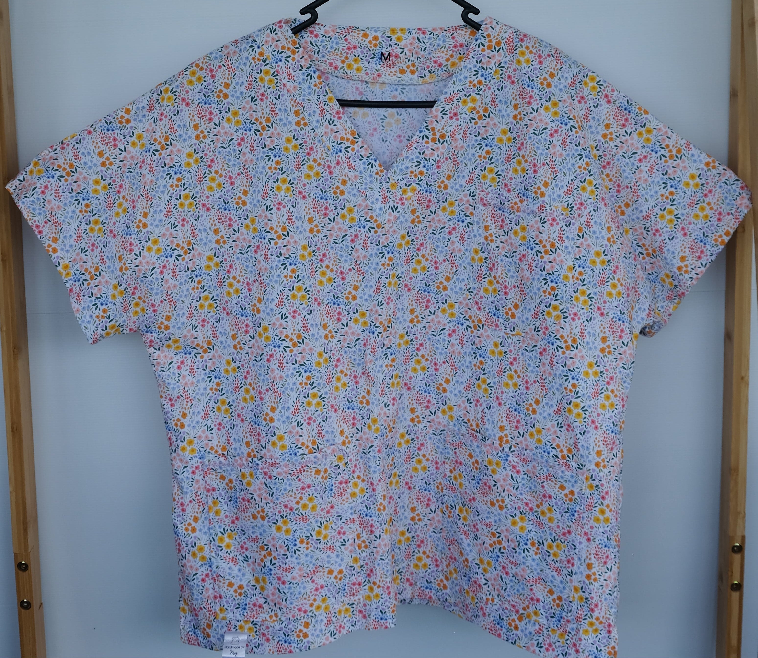 Floral-patterned scrub top on a hanger 